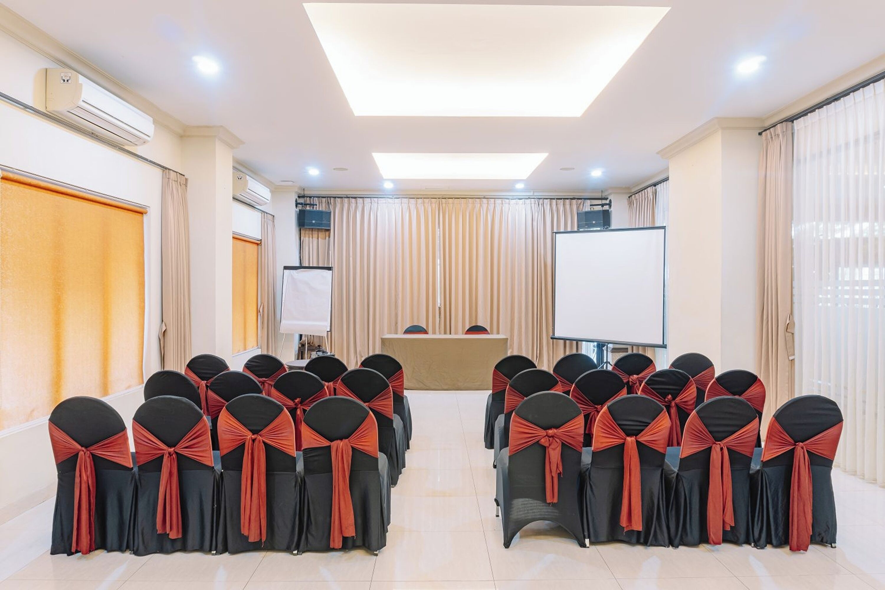 A conference room with rows of chairs, a podium, and a projection screen.