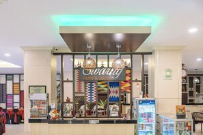Un área de descanso y lounge con un letrero, paneles decorativos y un dispensador de bebidas.