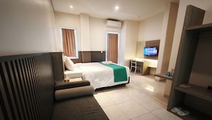 Una habitación de hotel con una cama, un escritorio, un televisor y un zapatero.