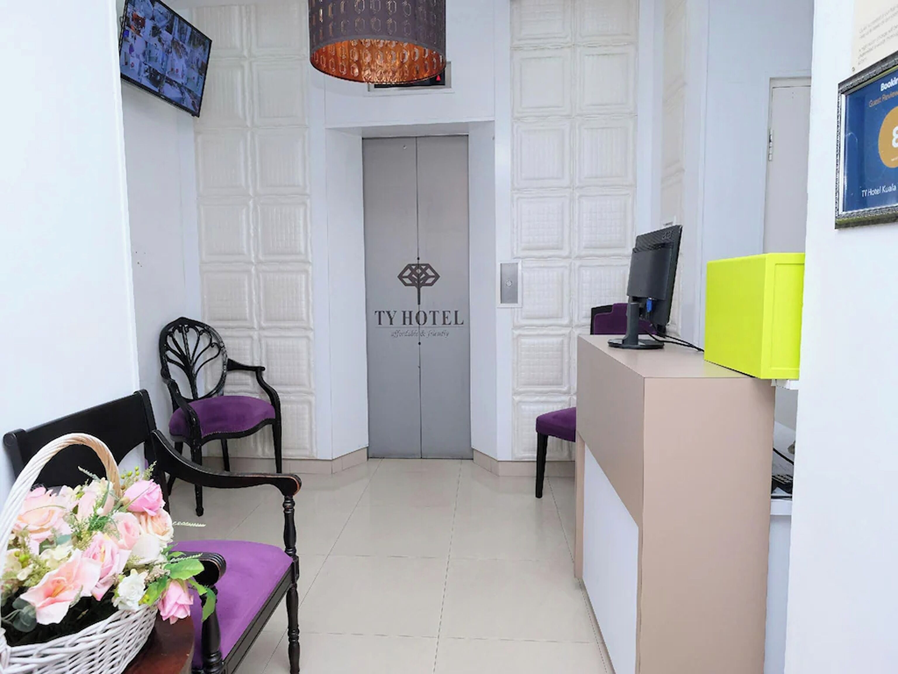 A reception area with a desk, two chairs, a television, and a door labeled 'TY HOTEL'.