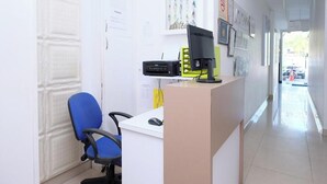 Mostrador de recepción con una computadora, una silla y una pared decorada con marcos.