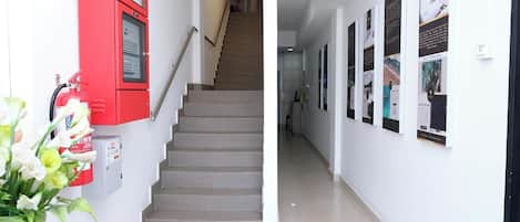 A reception area with a staircase, a fire extinguisher, and informational posters on the wall.