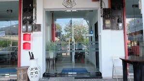 Un escaparate con puerta de cristal, un cartel que indica 'LOT 4857', y un pequeño espacio exterior con una mesa y sillas.
