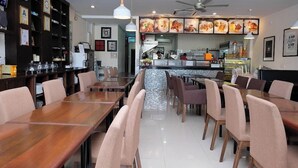 Un interior de restaurante con mesas y sillas de madera, una barra y un ventilador de techo.