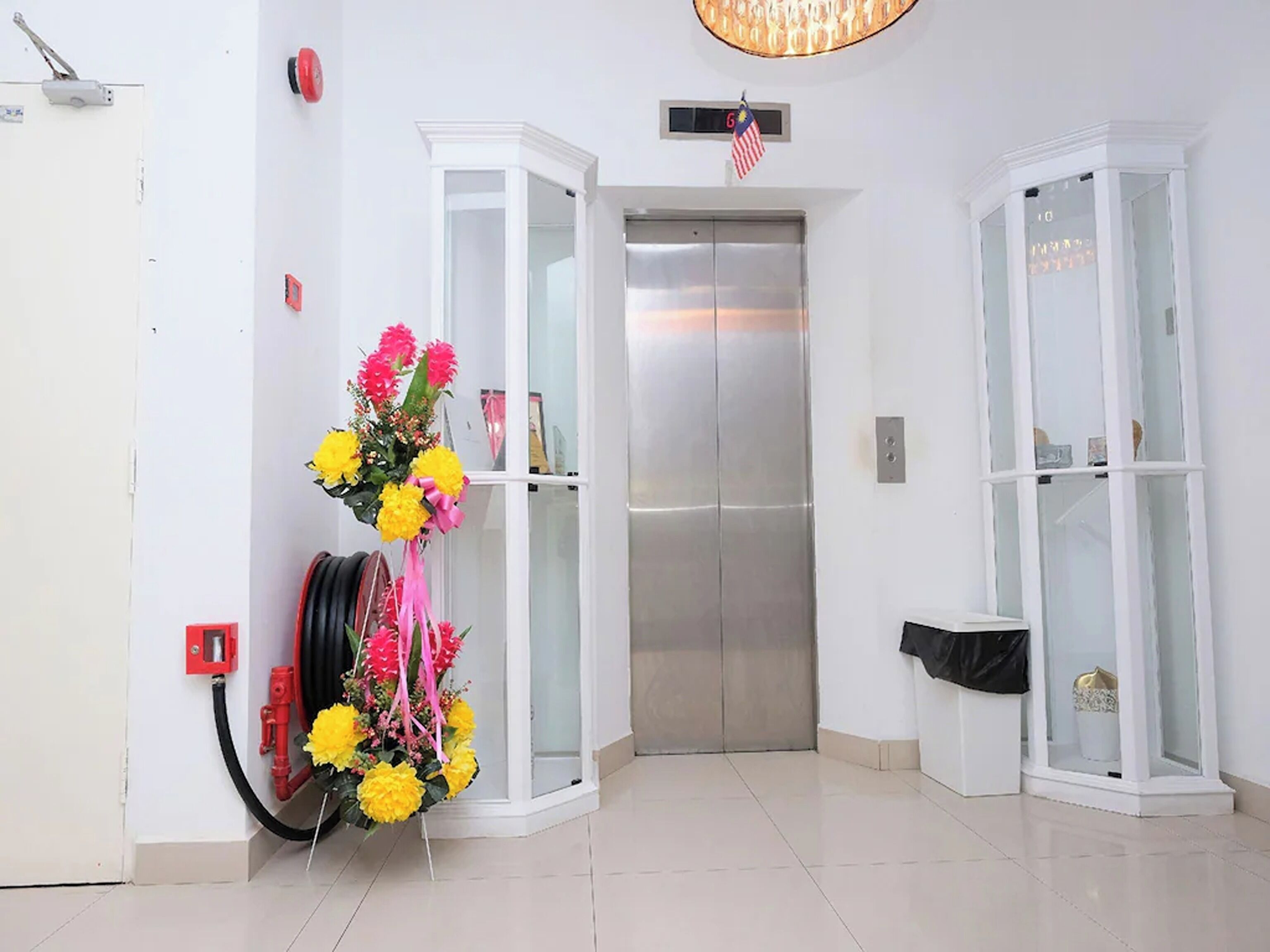 An elevator in a hallway with a floral arrangement on the wall.