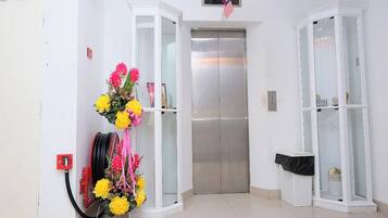 An elevator in a hallway with a floral arrangement on the wall.