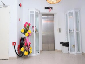 An elevator in a hallway with a floral arrangement on the wall. - Ty Hotel (Kuala Terengganu)