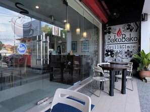 A restaurant with a glass facade, outdoor seating, and a mural on the wall. - Ty Hotel (Kuala Terengganu)
