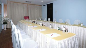 Una sala de conferencias con una larga mesa, sillas y una pantalla de proyector.