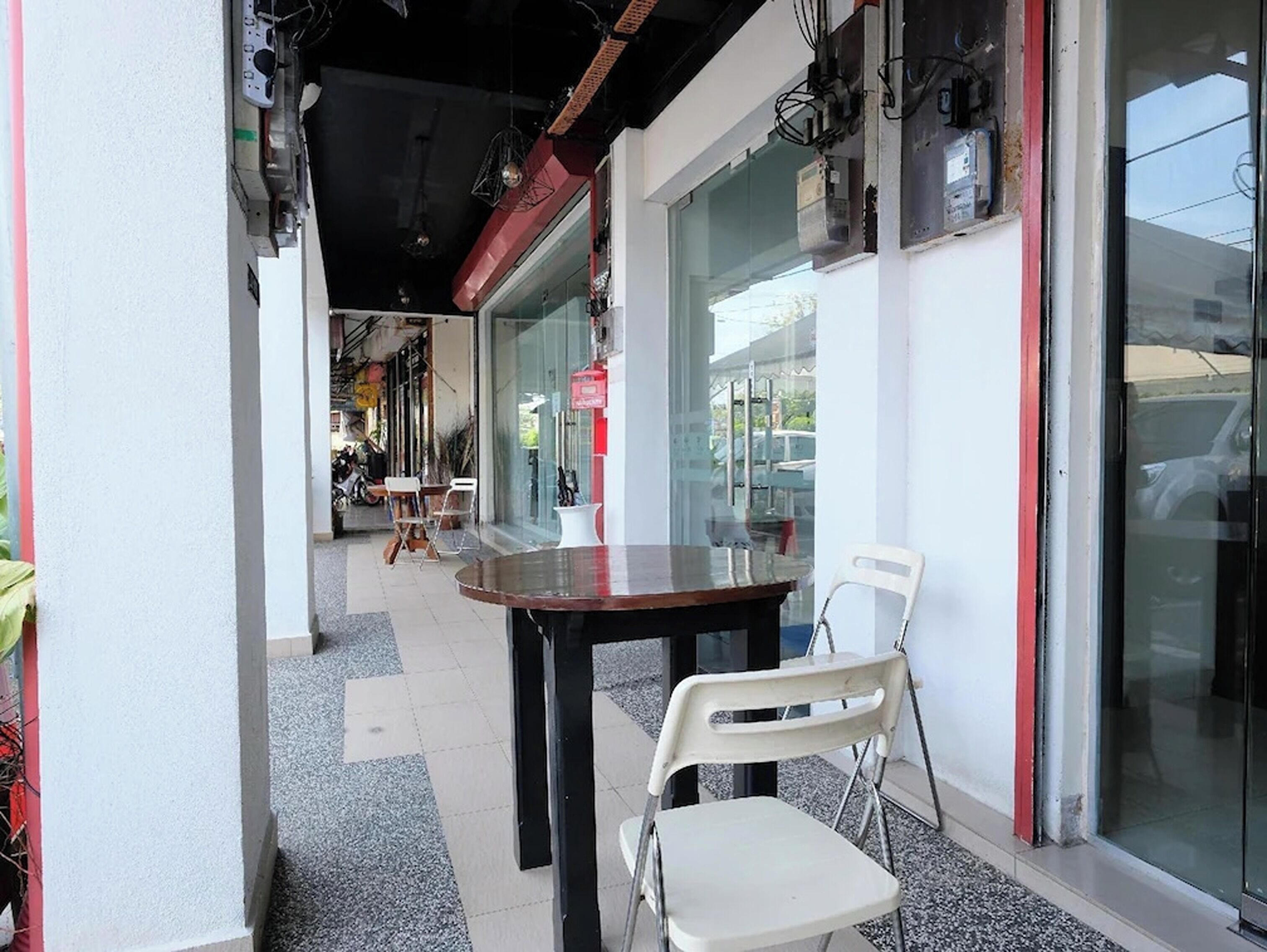 An outdoor seating area with a table and chairs, a glass storefront, and a red-brick building facade.