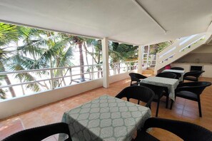 A covered outdoor seating area with tables and chairs, a staircase, and a view of palm trees. - Shenna's Beach Resort Boracay (Boracay Island)