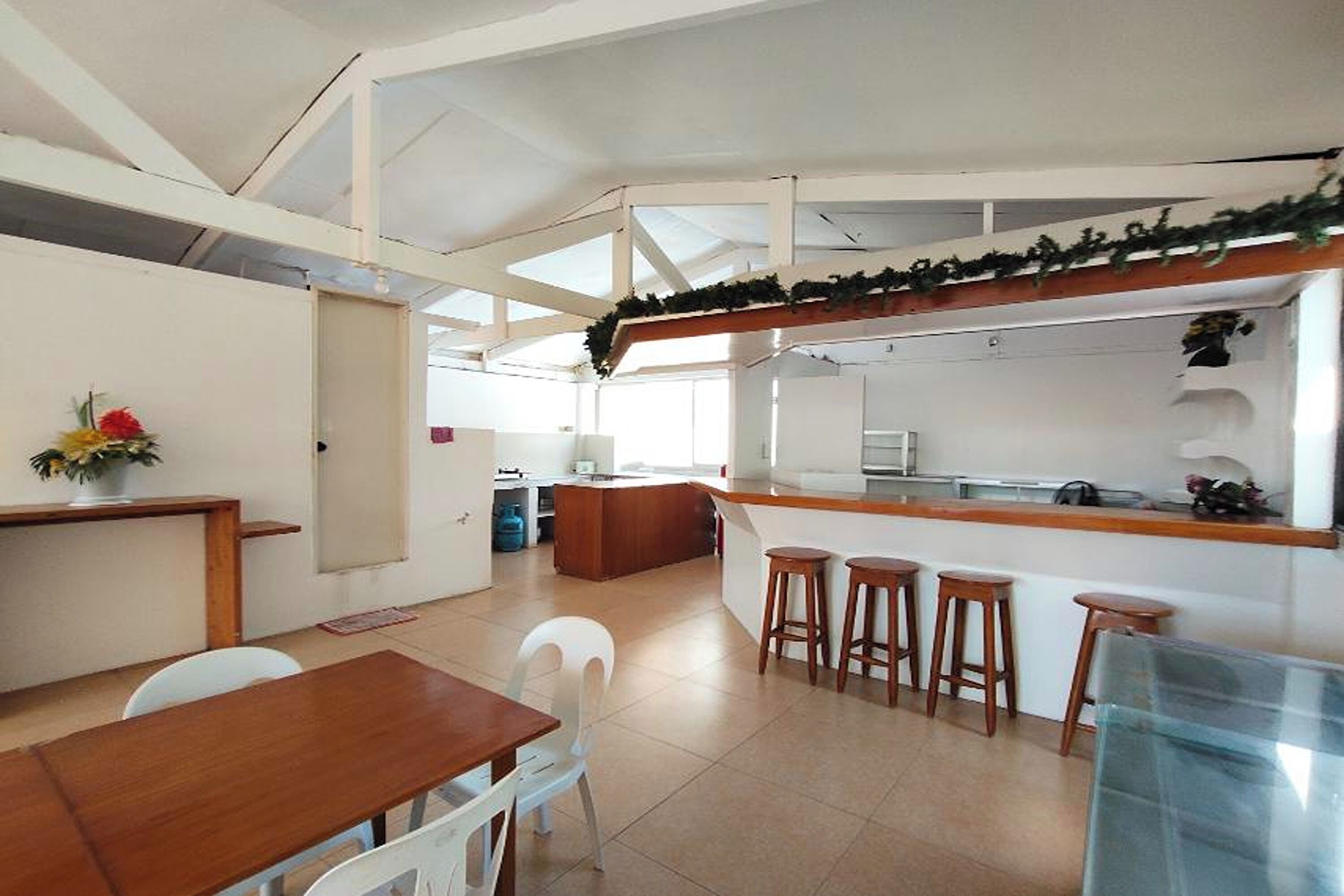 A spacious kitchen with a central island, white chairs, and a dining table.