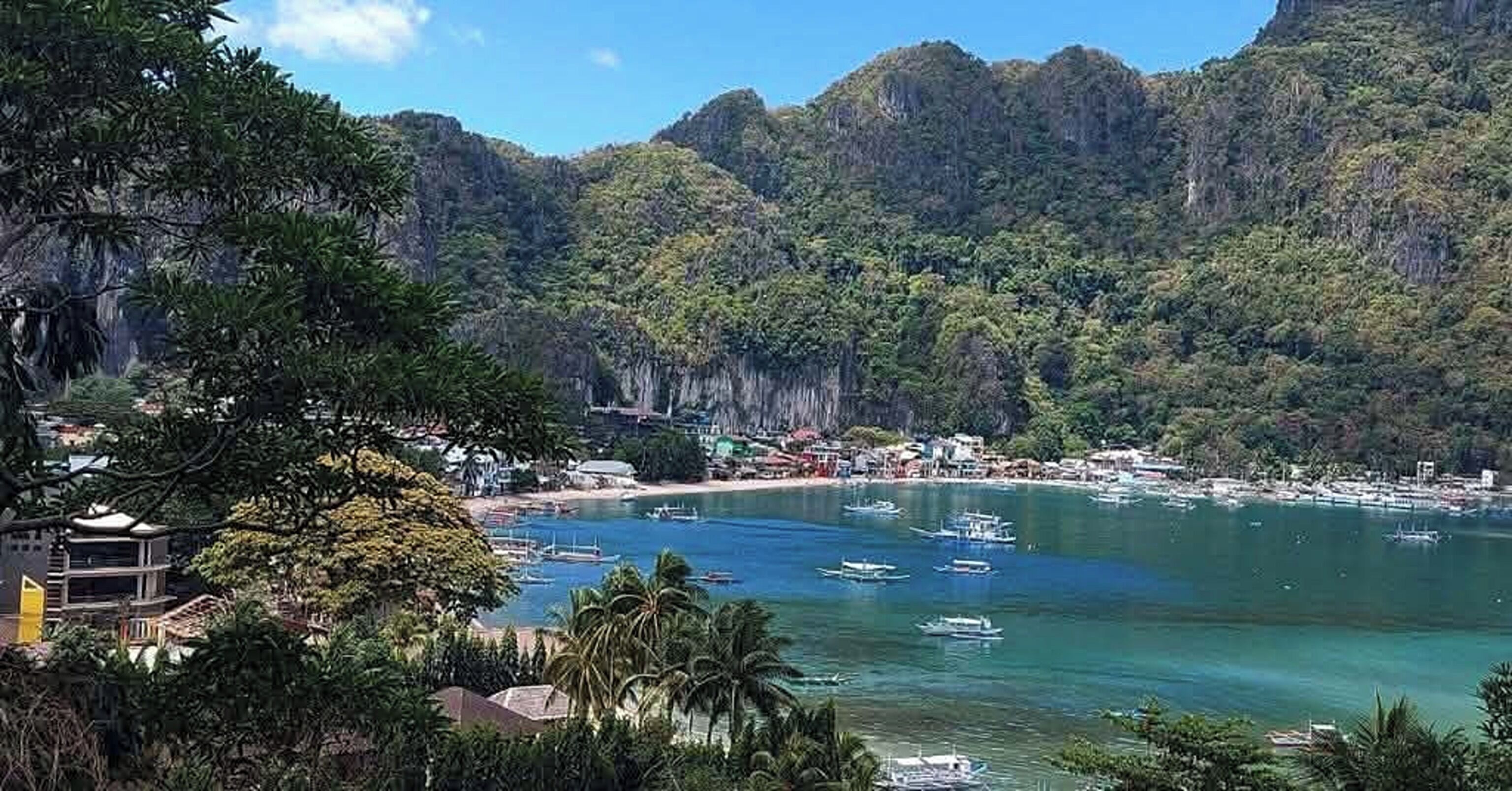 Uma região costeira com barcos, uma praia e terreno montanhoso.