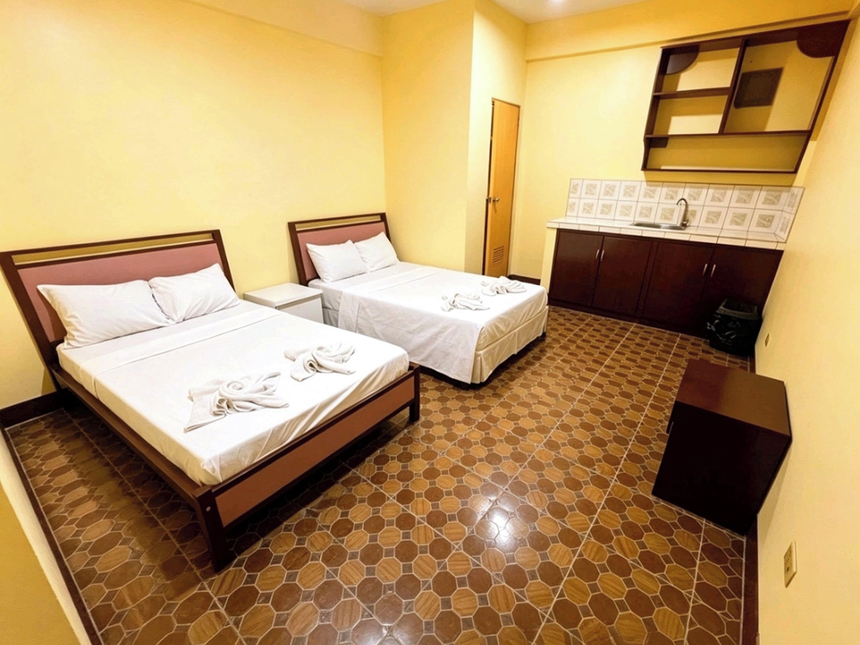 Une chambre d’hôtel avec deux lits, une petite kitchenette et une salle de bain.