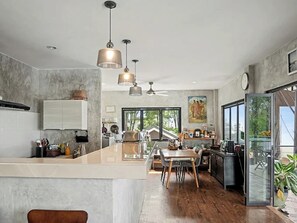 A modern kitchen with a central island, pendant lighting, and a view of the outdoors. - Para Hill Homestay (Pa Klok)