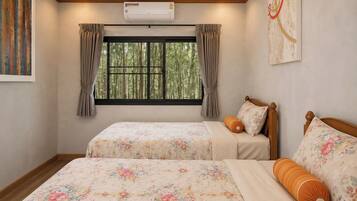 Un dormitorio con dos camas, una ventana con cortinas, un equipo de aire acondicionado y un cuadro en la pared.