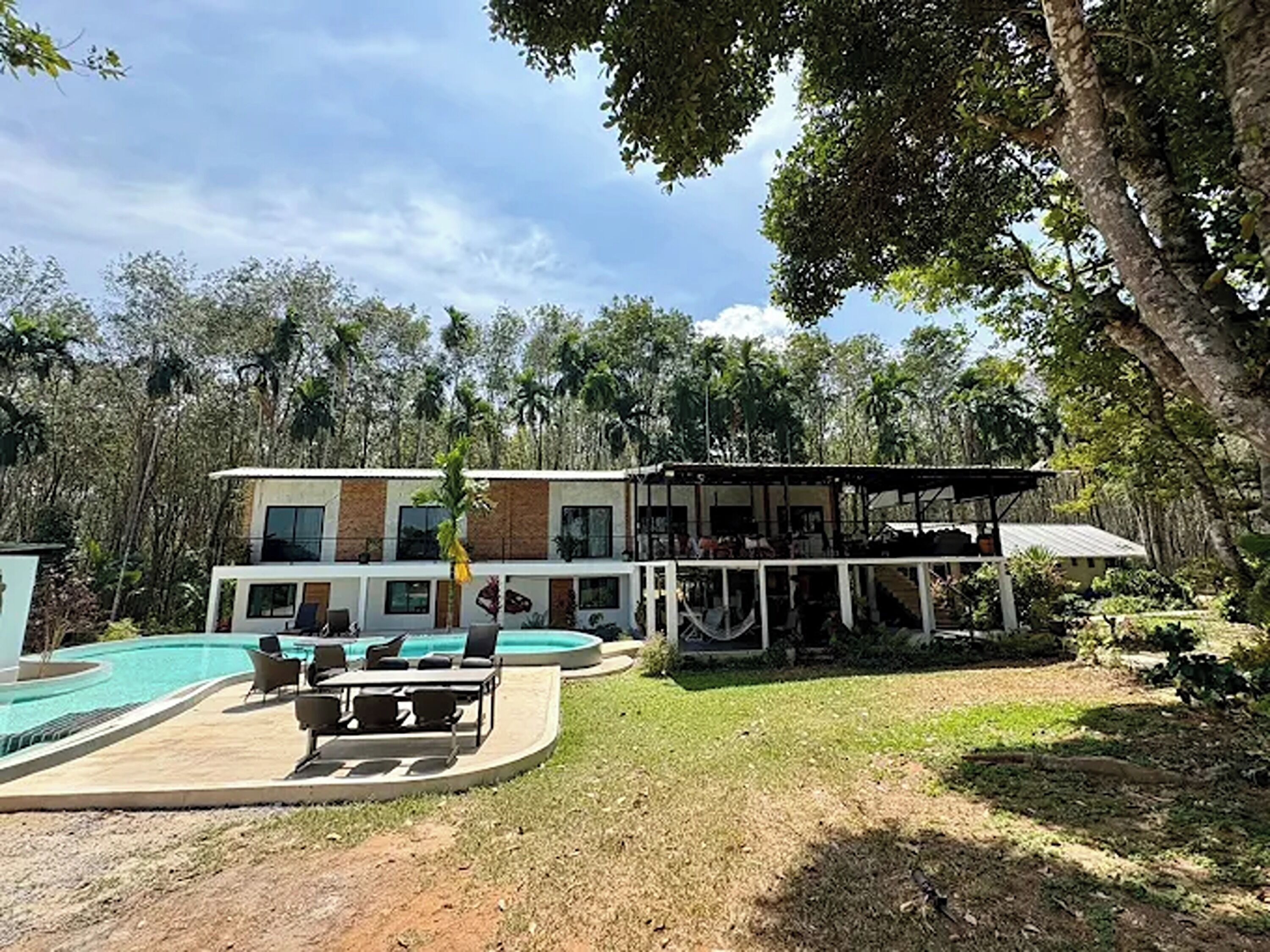 A modern two-story building with a swimming pool and outdoor seating area.