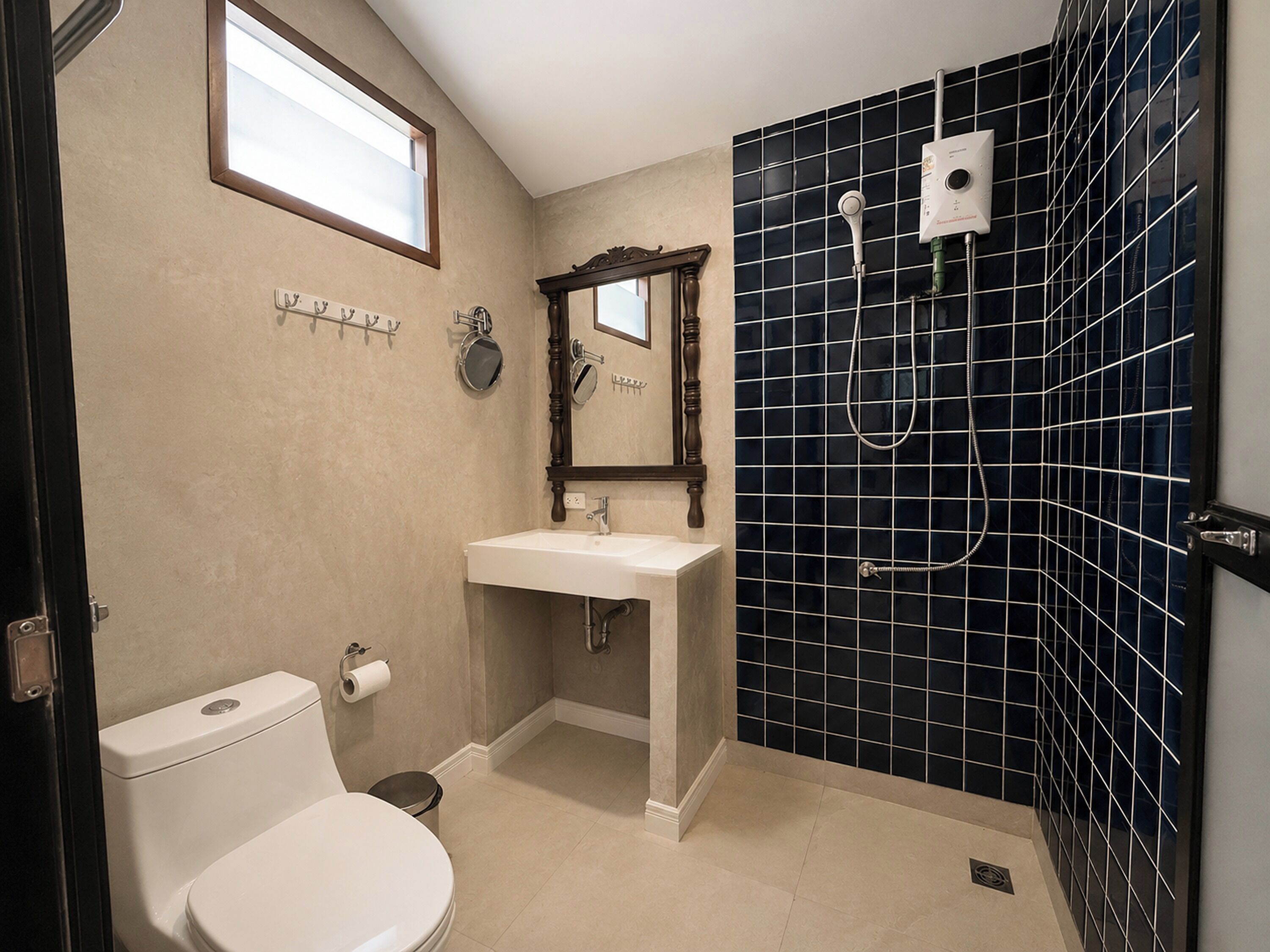 A bathroom with a toilet, sink, mirror, and shower.