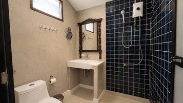 A bathroom with a toilet, sink, mirror, and shower.