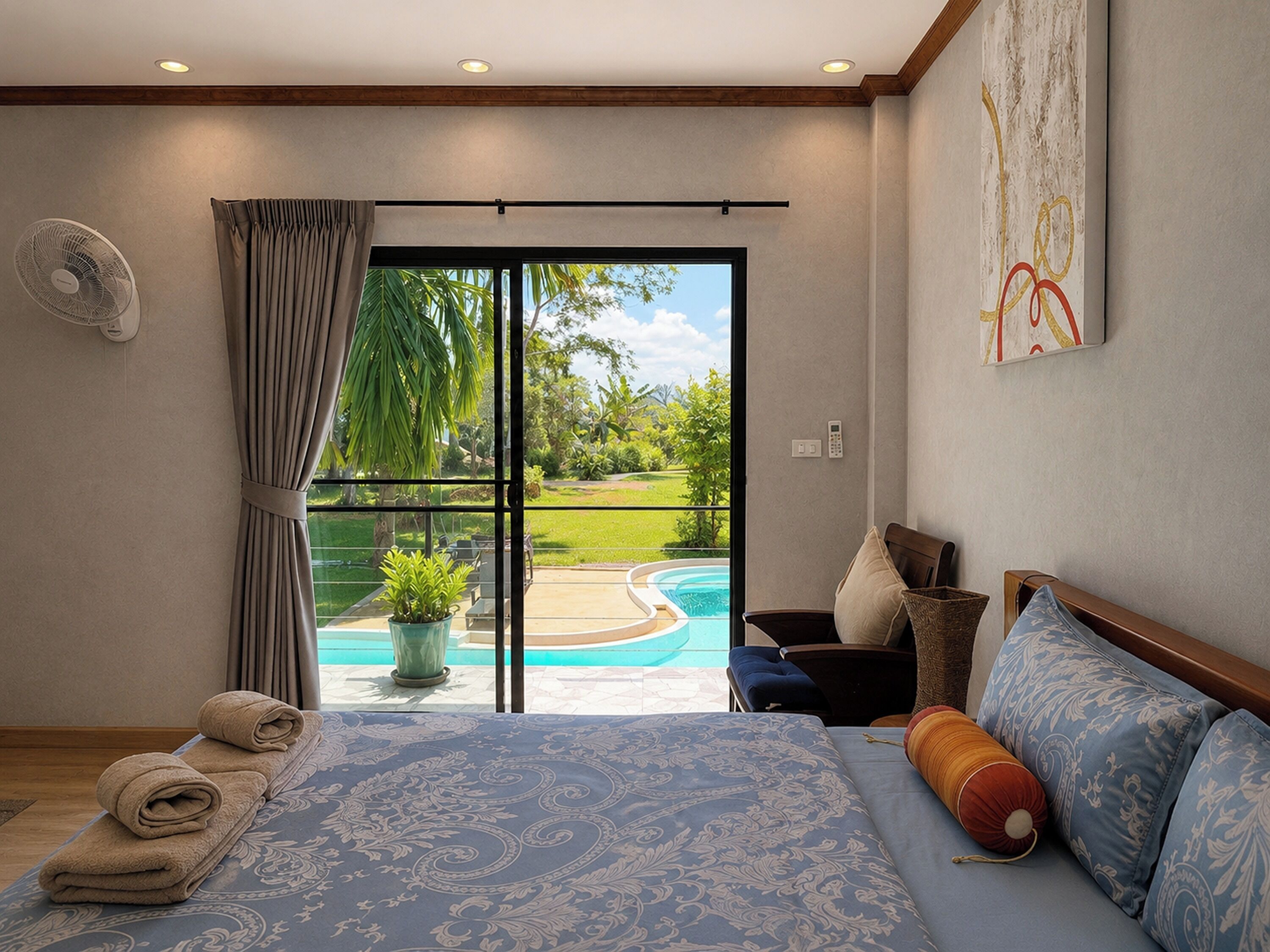 Un dormitorio con cama, vistas a una piscina, un ventilador y un cuadro en la pared.