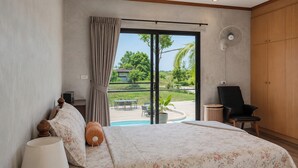 A bedroom with a bed, a chair, a fan, and a view of a pool and greenery. - Para Hill Homestay (Pa Klok)