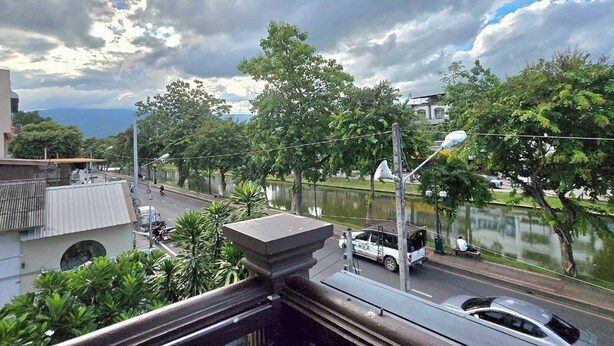 Un balcón con vistas a una calle, árboles y una masa de agua.