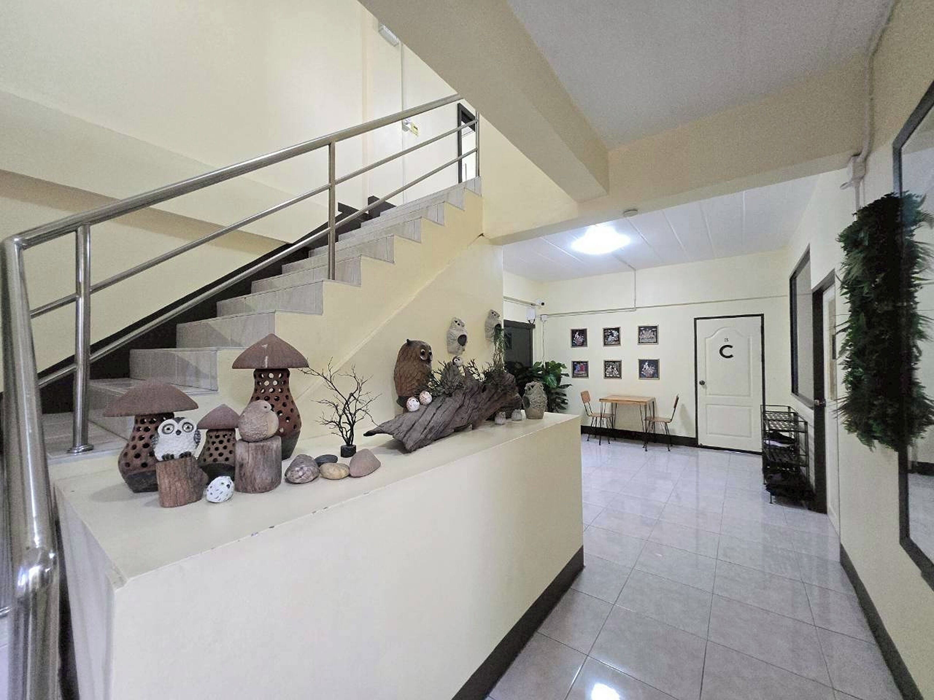 A staircase with a metal railing, a wall with framed pictures, and a door labeled 'C'.