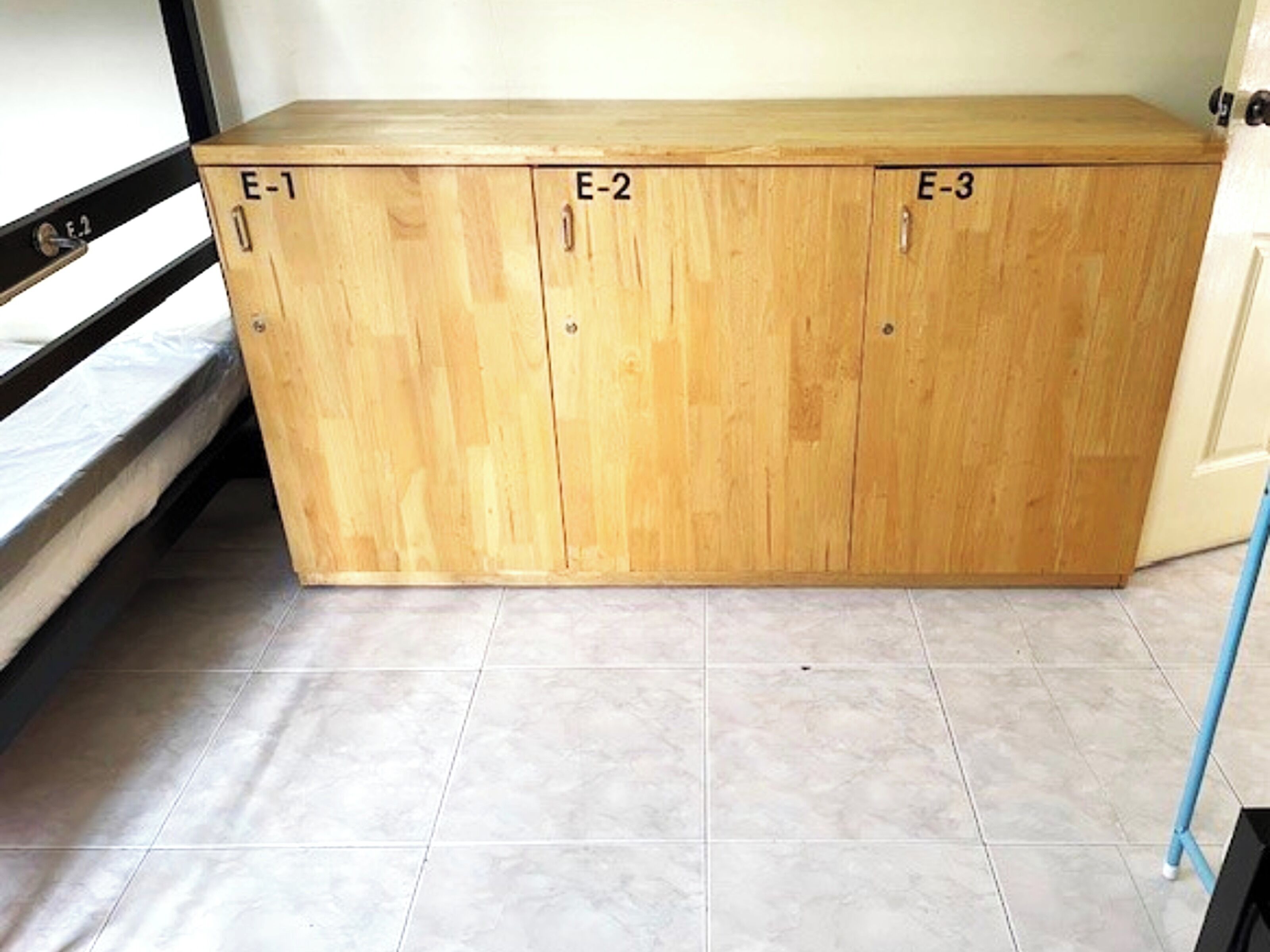 Ein Holzkabinent mit drei Abteilungen, beschriftet mit E-1, E-2 und E-3.