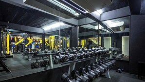 Un gimnasio con paredes de espejo, estantes para pesas y equipo de ejercicio.