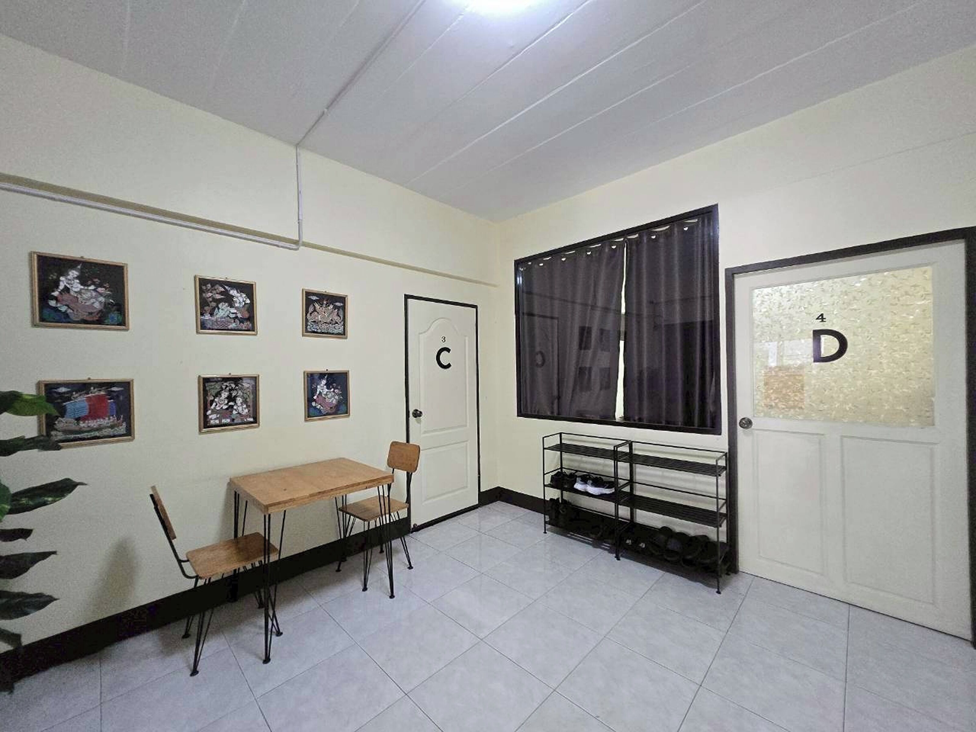 A room with a wooden table, chairs, a shoe rack, and framed pictures on the wall.