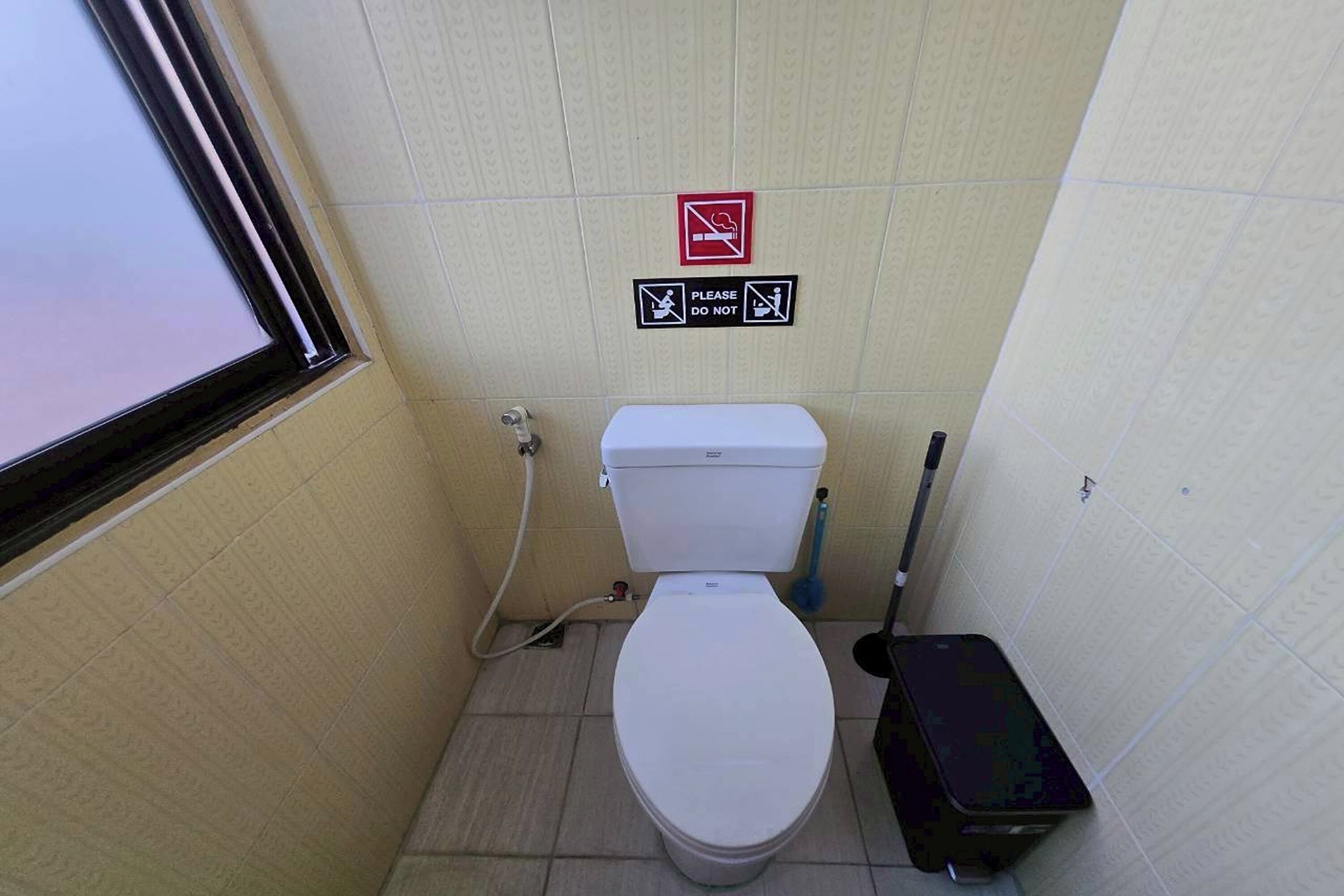 A small bathroom with a toilet, a bidet, and a trash bin.