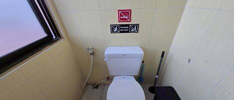 A small bathroom with a toilet, a bidet, and a trash bin.