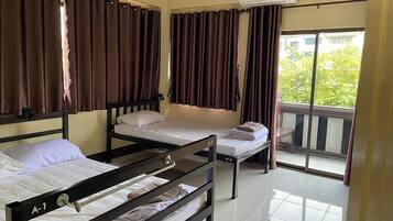 Quarto com duas camas de solteiro, janela com cortinas, ar condicionado e varanda.