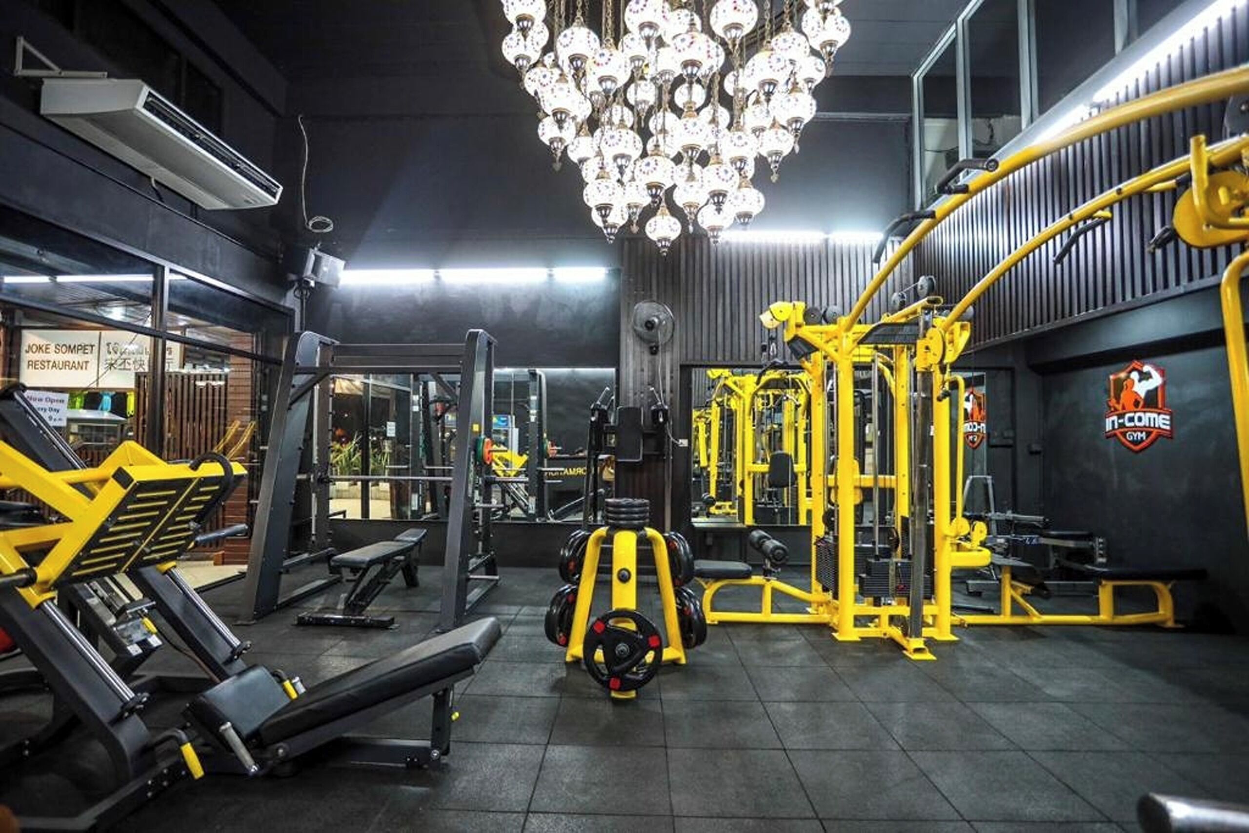 Uma academia com equipamentos de musculação, esteira e espelho.