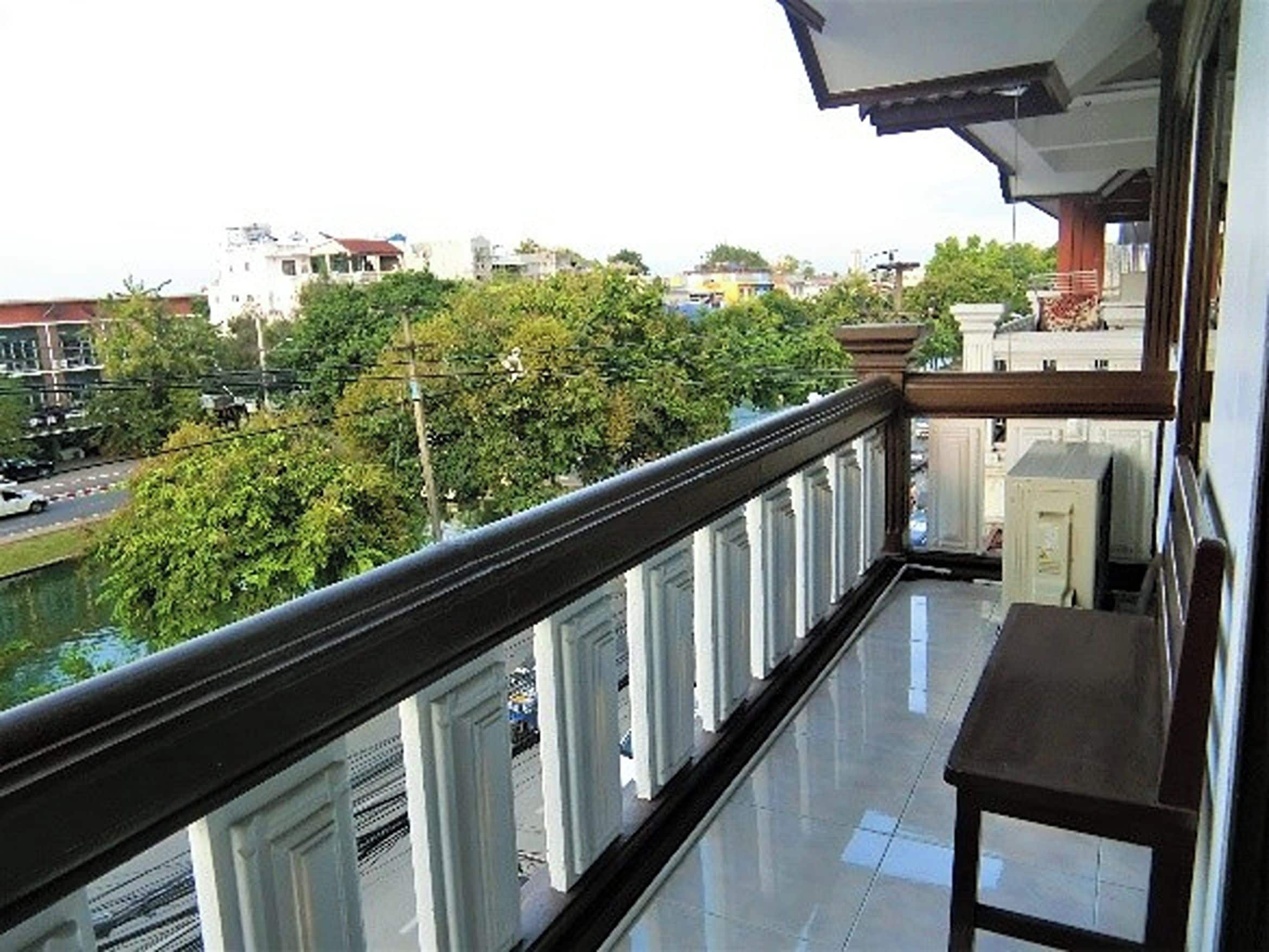 Un balcon donnant sur une rivière et des bâtiments, avec une balustrade et une table.