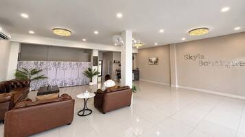 A spacious lobby with leather sofas, a reception desk, and a chandelier.
