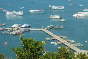 A marina with multiple boats docked, a pier extending into the water, and a large building with a distinctive roof structure. - Skyla Boutique Pattaya (Pattaya)