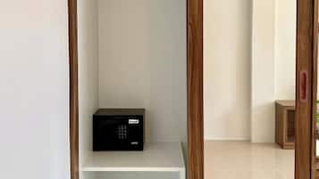 A closet with wooden doors, a black electronic device on the bottom shelf, and a white shelf above.