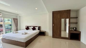 Une chambre d’hôtel moderne avec un grand lit, une armoire, une petite table de chevet et une grande fenêtre avec des rideaux.