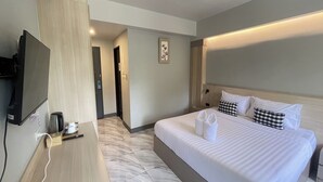 Hotellihuone, jossa on sänky, työpöytä, televisio ja kahvinkeitin.