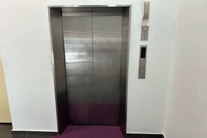 A metallic elevator with a purple carpet, a wall-mounted intercom, and a small ventilation panel. - Km Barakah Suite Kuala Terengganu (Kuala Terengganu)