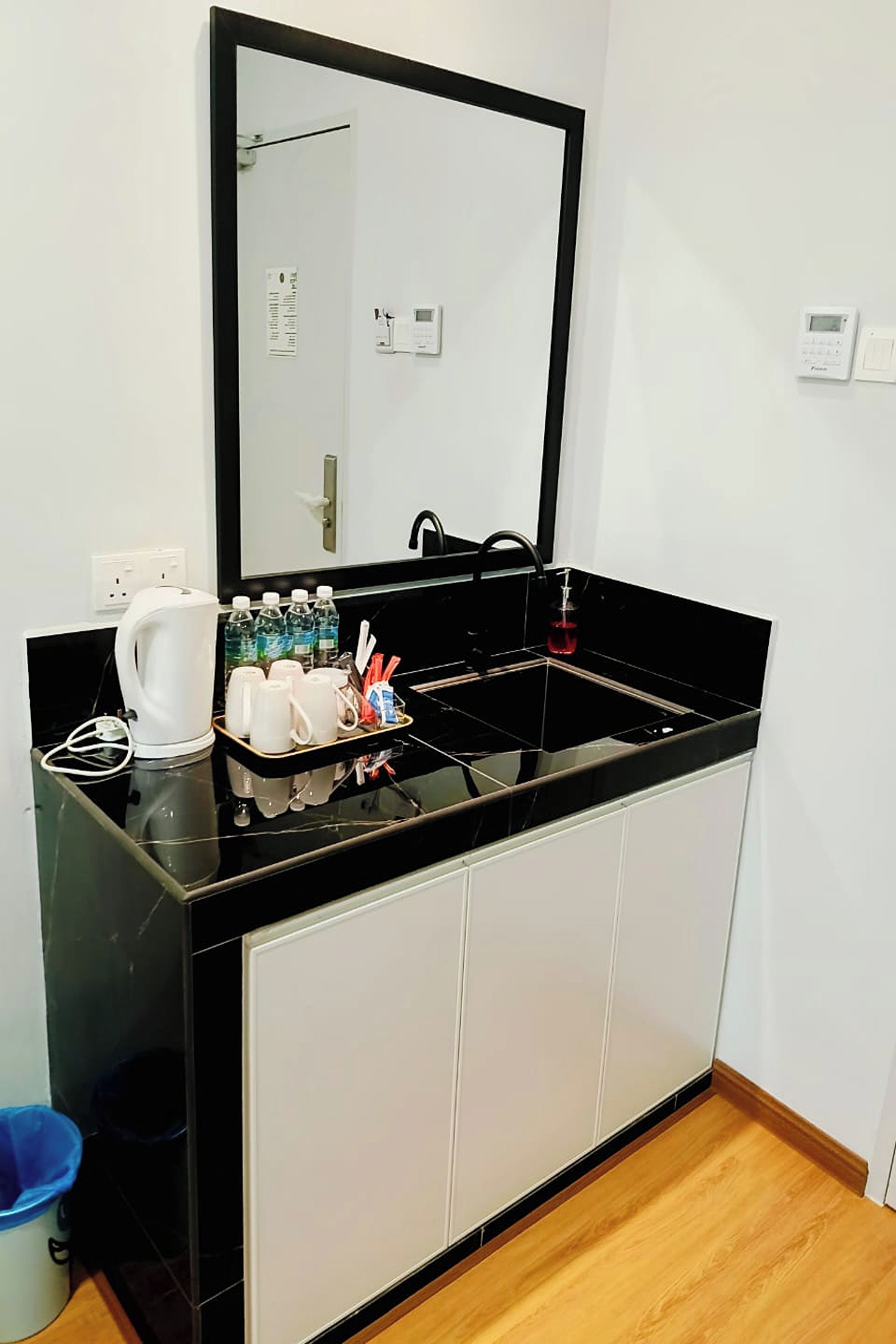 A modern bathroom with a black countertop, a large mirror, a sink, and a cabinet.