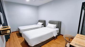 Ein Hotelzimmer mit zwei Einzelbetten, Holzboden, Schreibtisch und Stuhl.