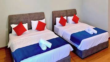 Dos camas individuales con cabeceras, ropa de cama blanca, almohadas rojas y colchas azules.