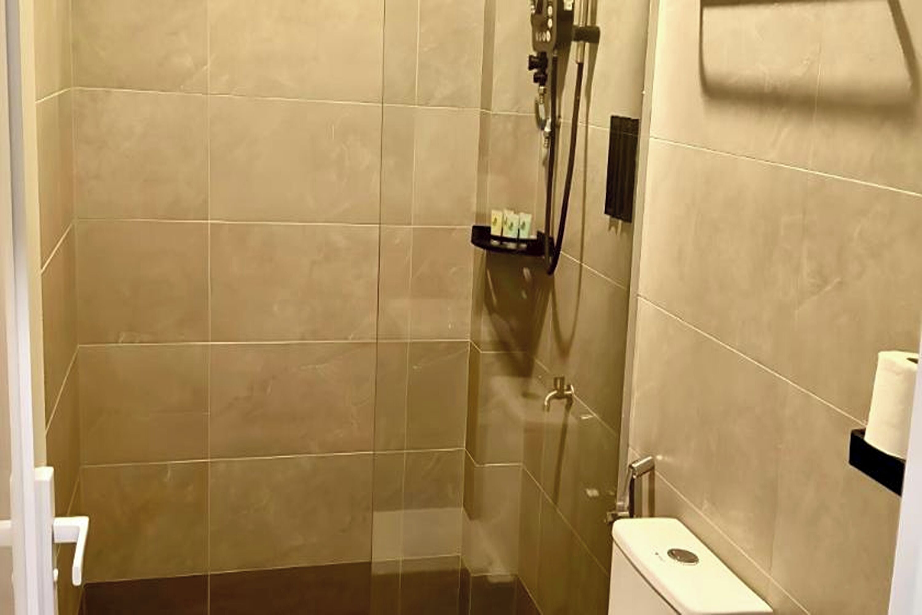 A shower with a glass door, a towel rack, and a toilet with a paper towel holder.