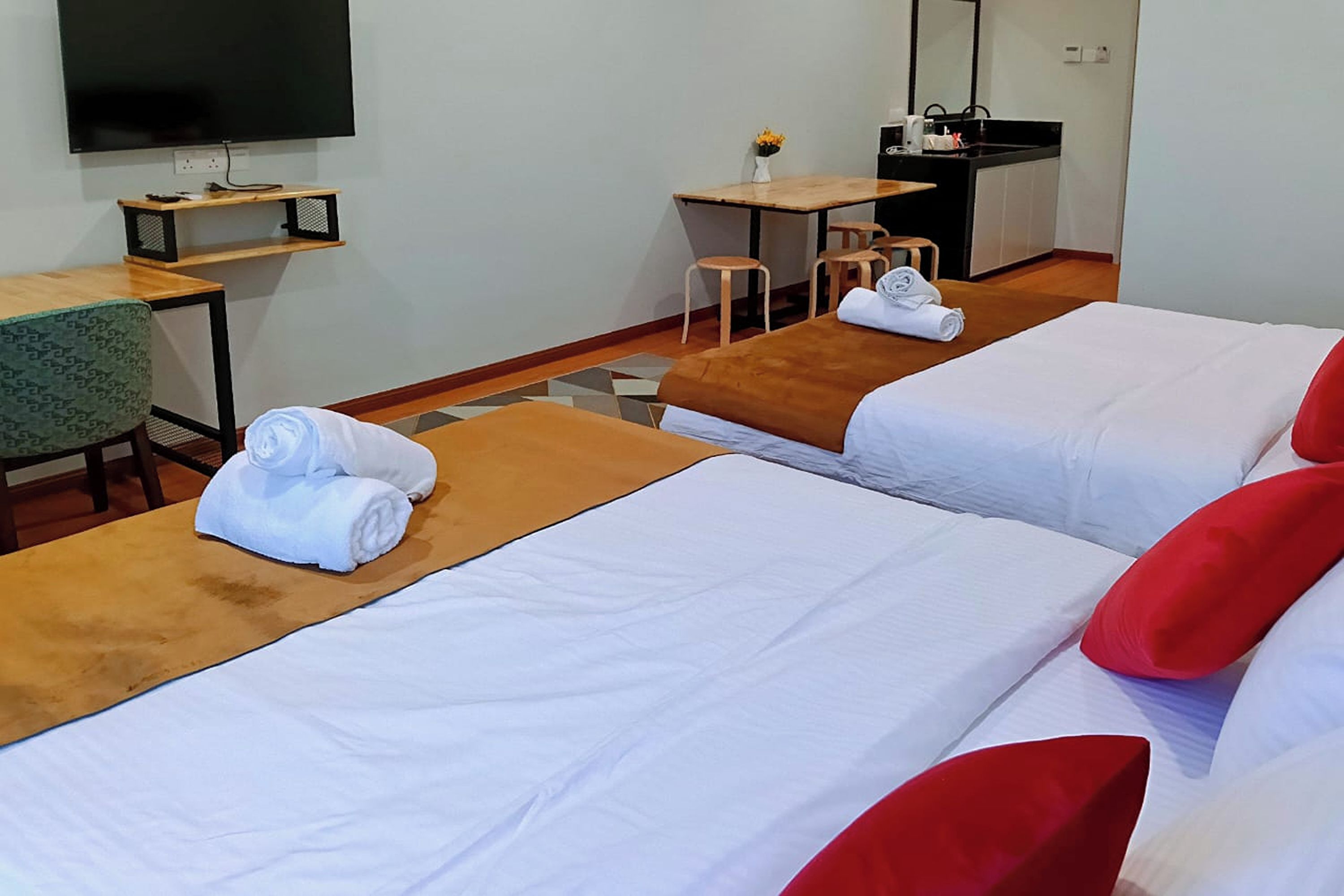 Habitació d'hotel amb dos llits, una taula de treball, televisió i una petita cuineta.