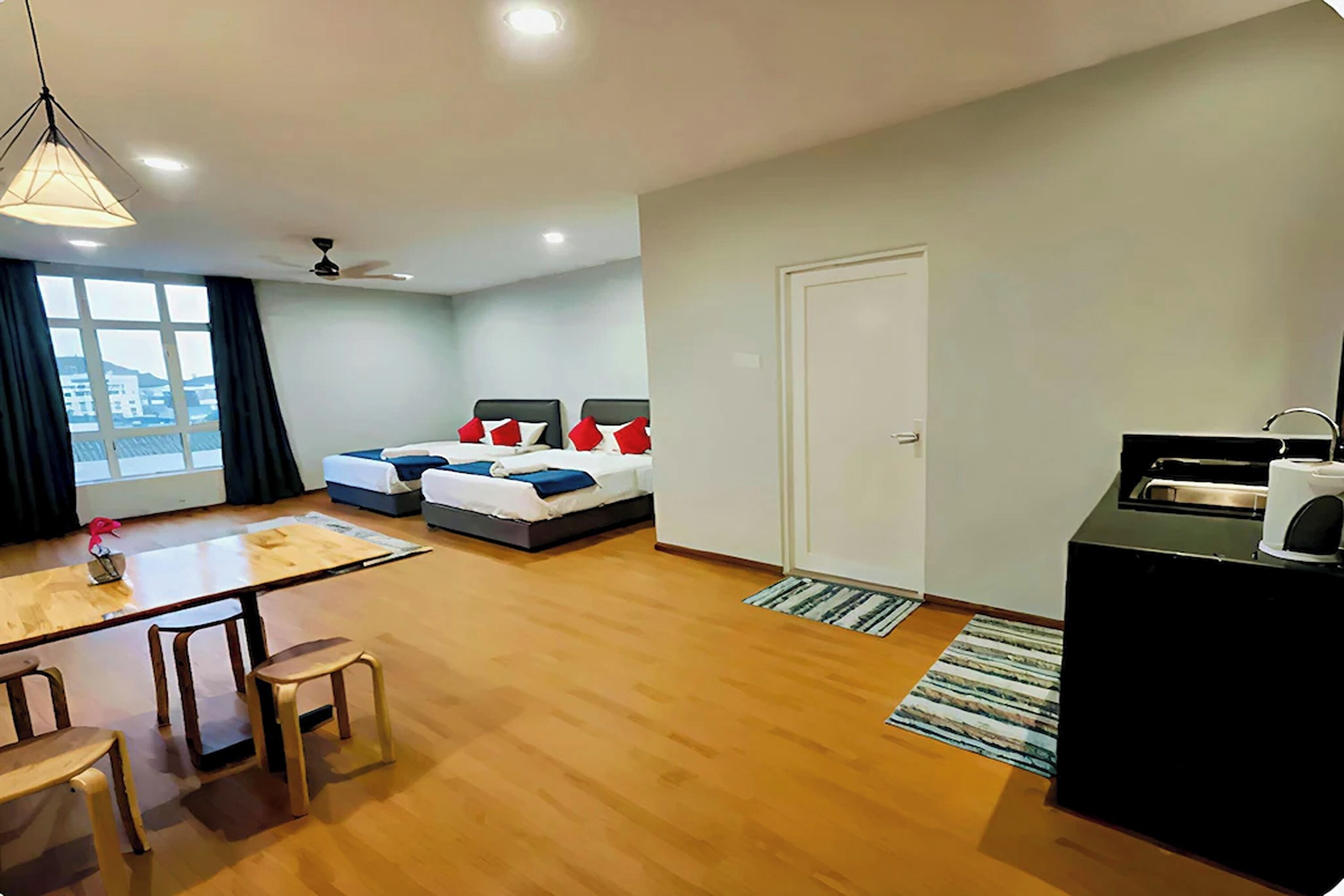 A hotel room with a bed, a desk, a chair, a window with curtains, and a door.