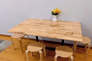 Una mesa rectangular de madera con un jarrón de flores amarillas encima, acompañada por dos taburetes redondos de madera.