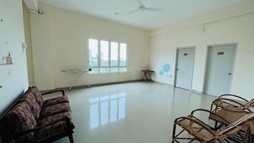 A spacious room with a ceiling fan, a large window, a couch, a table, and two doors.