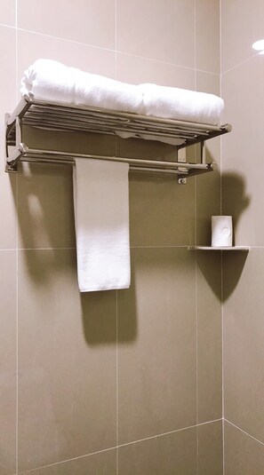 A bathroom with a towel rack holding a folded towel and a roll of toilet paper. - Alexis Kt Roomstay (Kuala Terengganu)